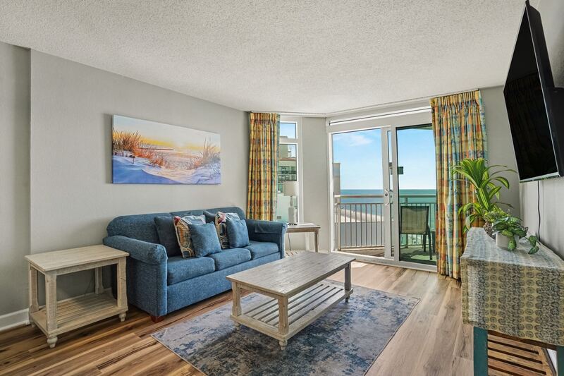 Furnished living room with sofa, wall-mounted TV and ocean view